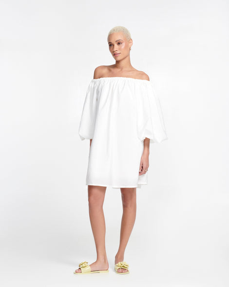Model in a white dress wearing a pair of green Babe Petals slide sandals