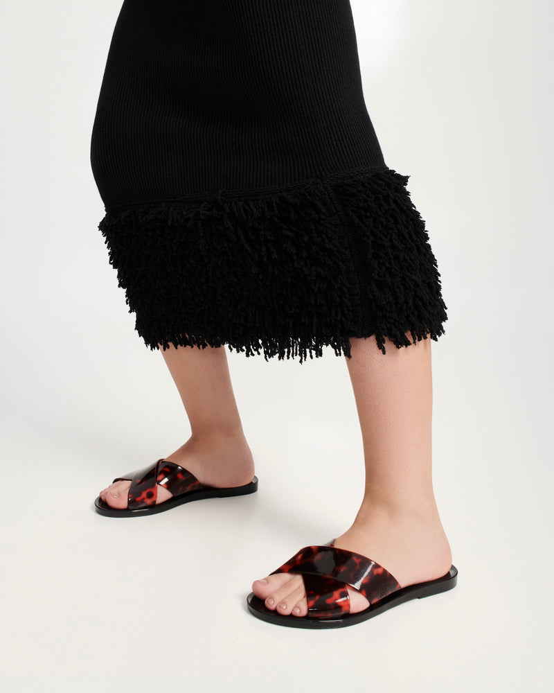 Models legs wearing a pair of black Essential Cross Slide sandals with tortoise colored straps
