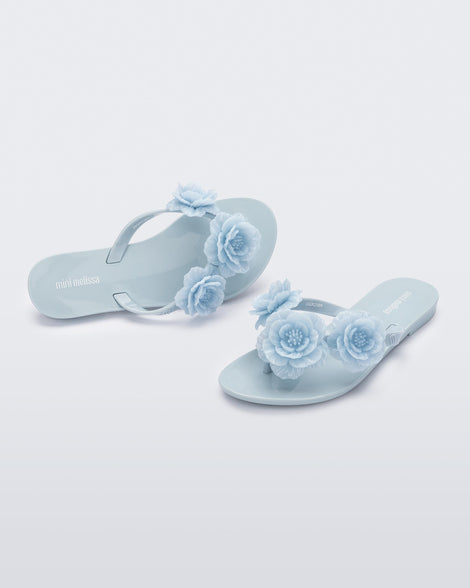 Angled view of a pair of a blue Harmonic Springtime kids flip flop with three blue flowers.