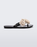 Side view of a black Harmonic Springtime kids flip flop with three beige flowers.