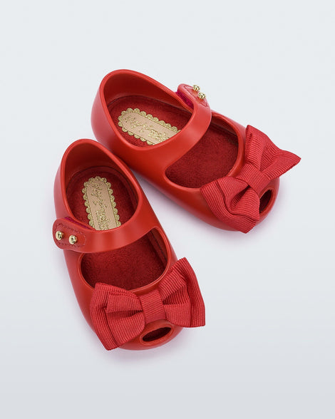 Top view of a pair of red Mini Melissa My First wit a red bow.