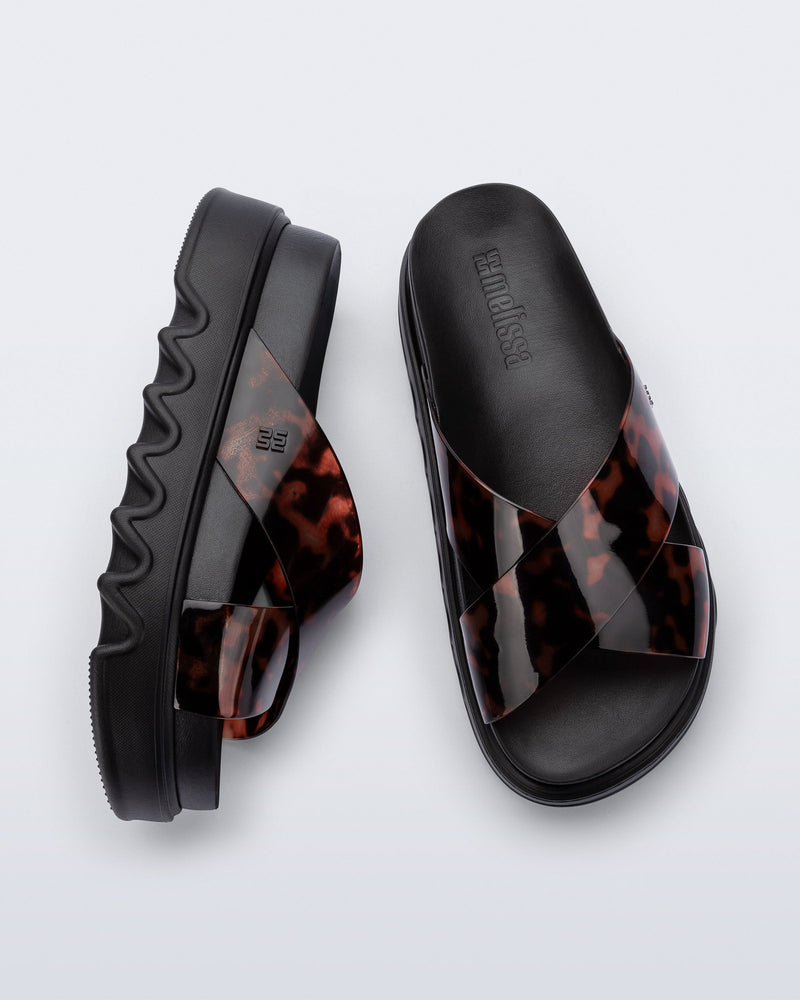 Top and side view of a pair of black/tortoise Cozy Cross platform sandals with crisscross top straps