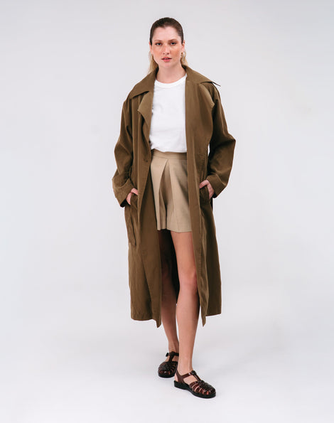 Woman wearing a long brown coat over a white shirt and beige skirt and a pair of clear brown Possession fisherman sandals