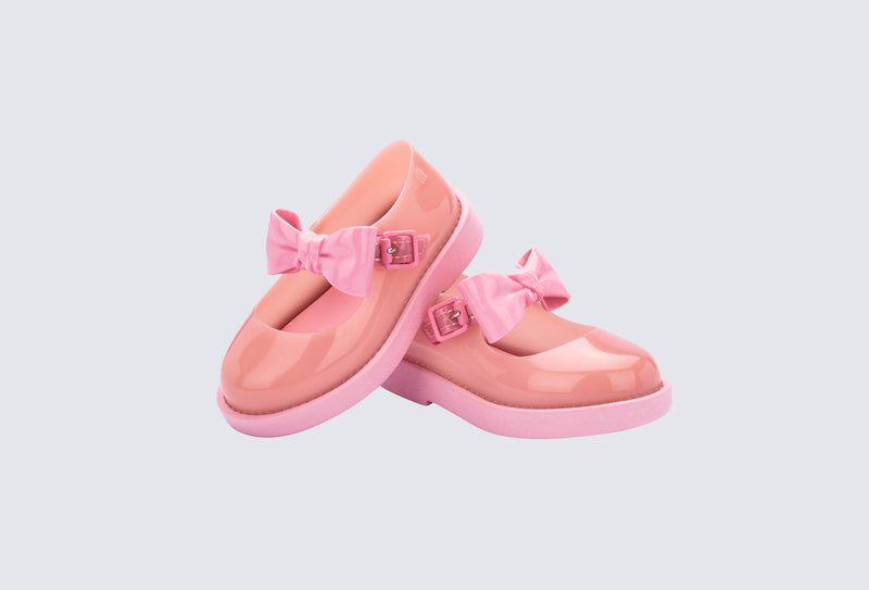 Angled view of a pair of pink Blair baby mary janes with bow in the strap