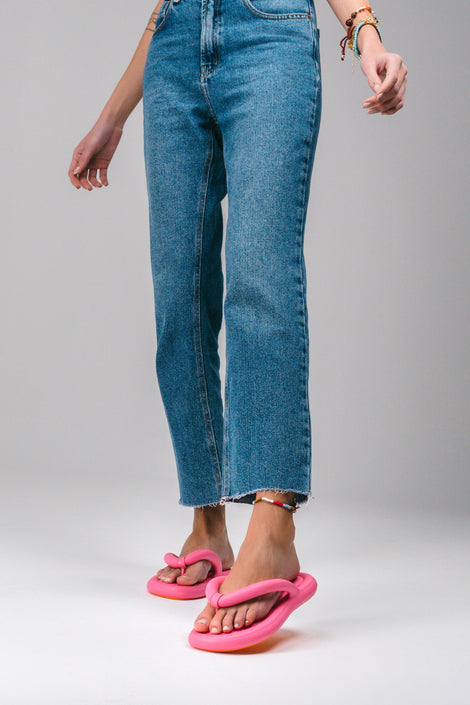 A model's legs in cut off jeans wearing a pair of pink Melissa Free Flip Flops with puffer-like straps.