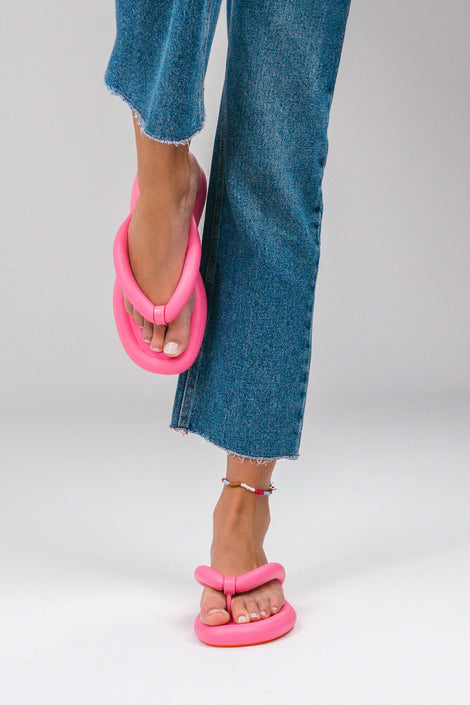 A model's legs in cut off jeans wearing a pair of pink Melissa Free Flip Flops with puffer-like straps.