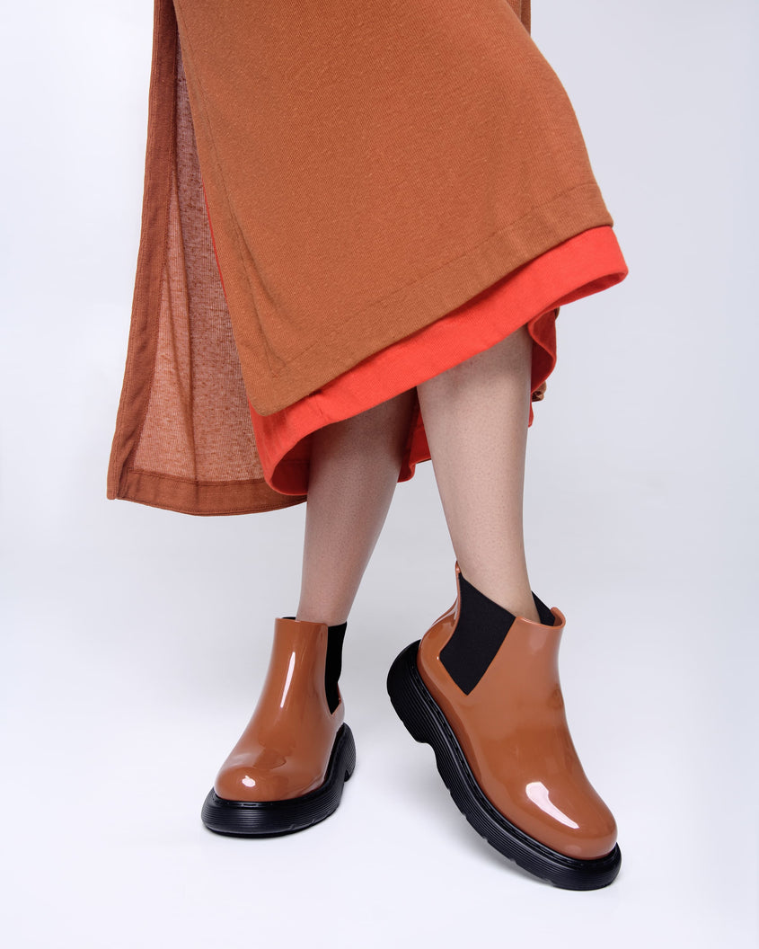 Models legs wearing a pair of brown/black Melissa Step boots.