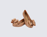 Angled view of a pair of beige Ultragirl Sweet X kids flats with a bow that has chrome flowers on it