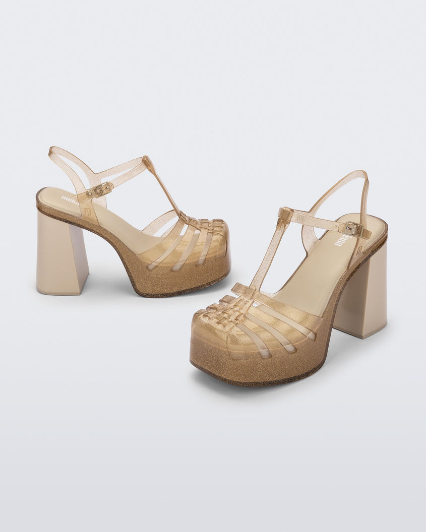 Side and angled view of a pair of beige glitter gold Melissa Party platform heel.