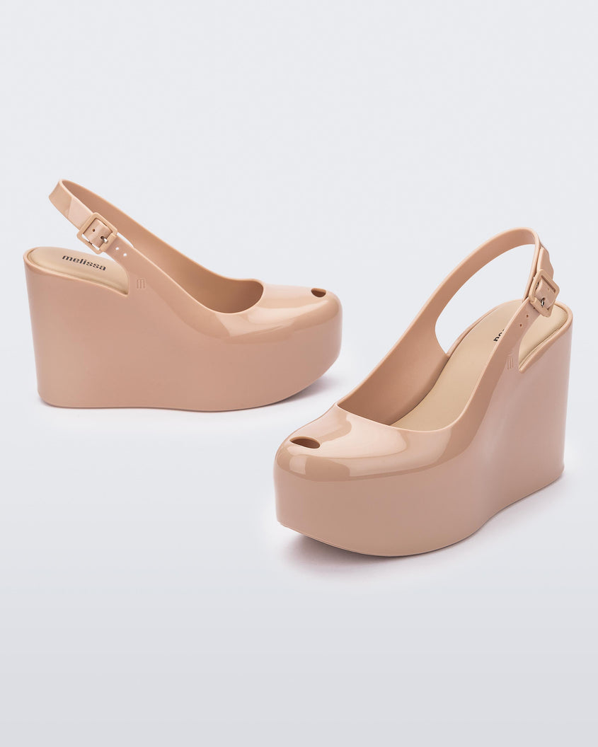 Side and angled view of a pair of beige Melissa Groovy wedge platform slingback heels with peep toe.
