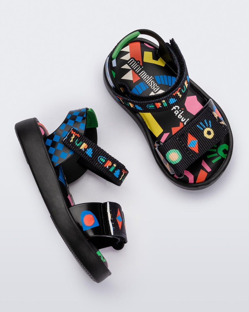 Top and side view of a pair of black and blue patterned Mini Melissa Pula Pula + Fabula sandals.