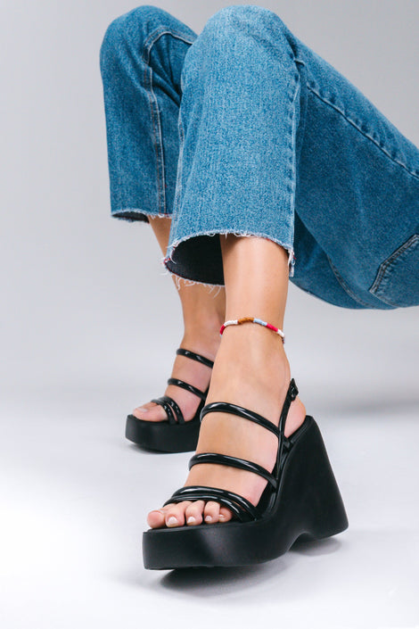 Model's legs in cut off jeans wearing a pair of black Jessie platform strappy wedges