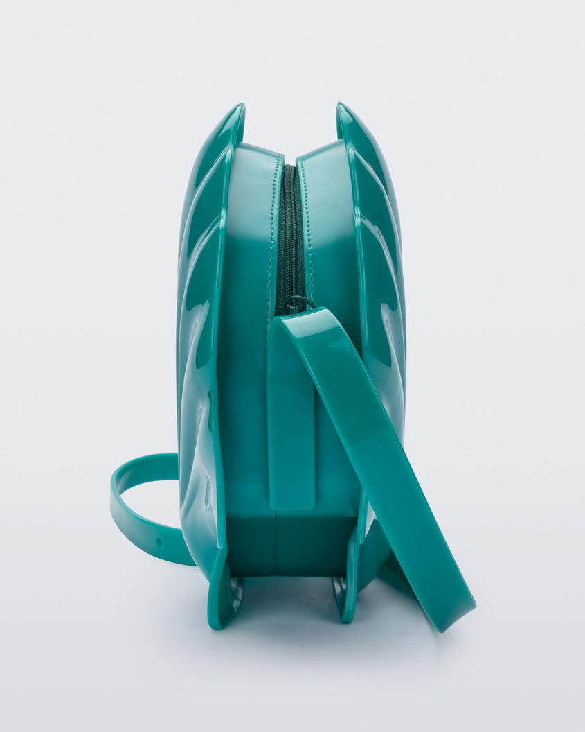 Side view of a iridescent blue Melissa Shell + Disney Little Mermaid bag with strap.