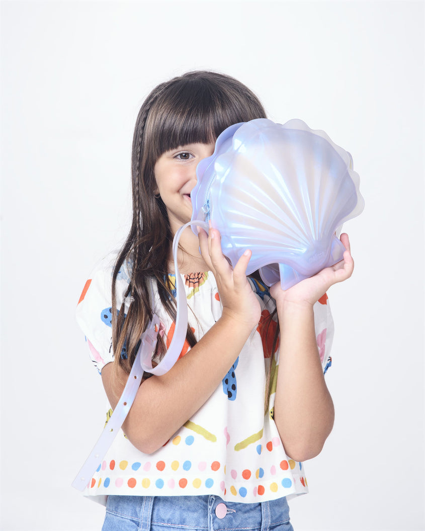 Girl holding a pearly blue Melissa Shell + Disney Little Mermaid bag with strap.