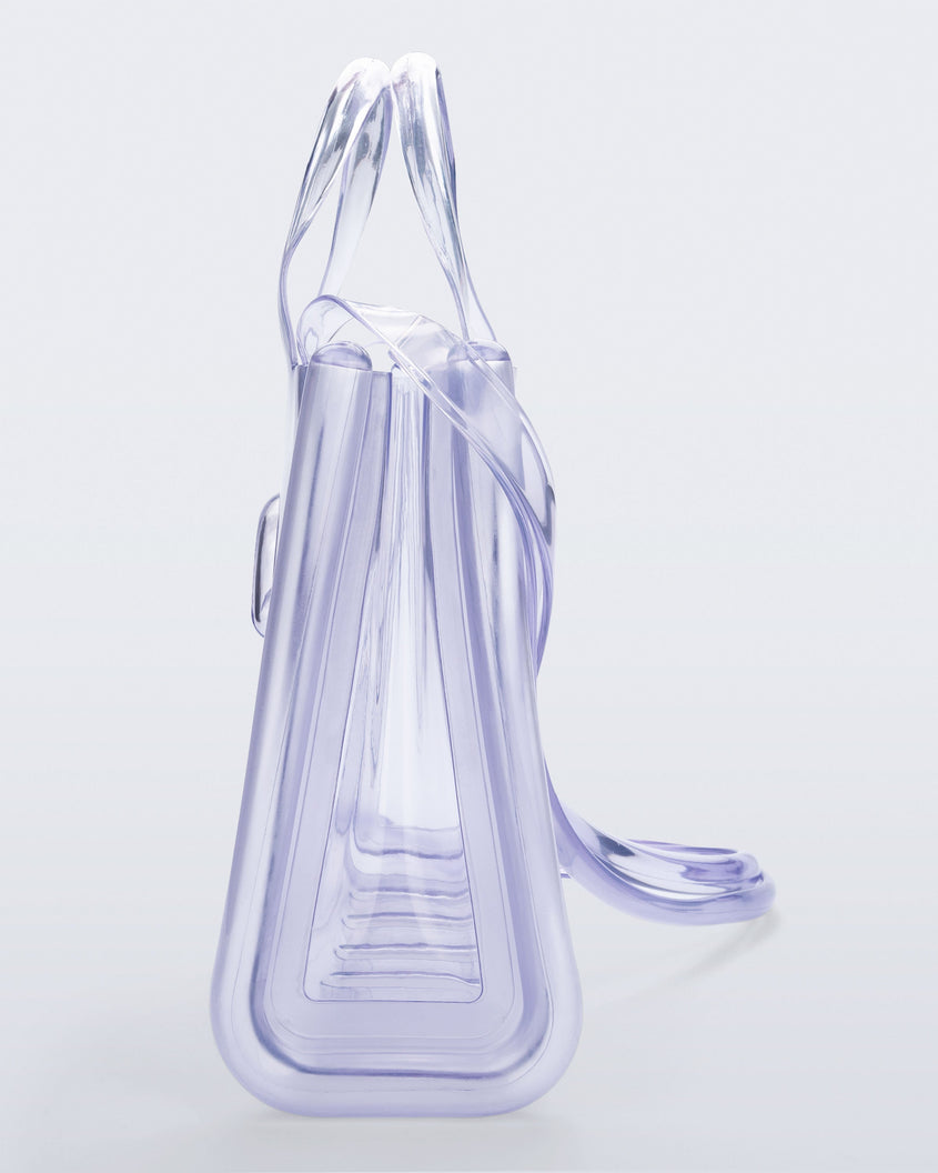 Side view of a clear Melissa Medium Jelly Shopper + Telfar bag with handles and a body strap