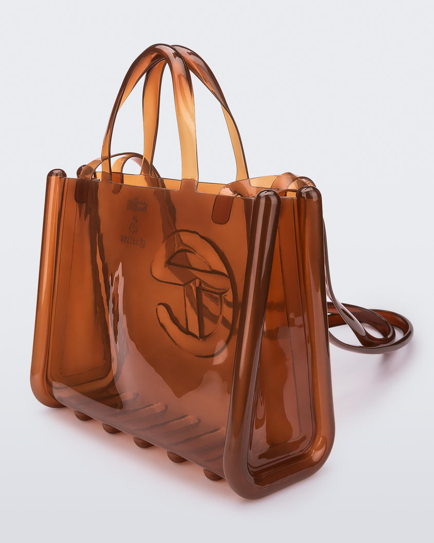 Angled view of a brown medium Melissa Jelly Shopper bag + Telfar bag with a handle and straps.