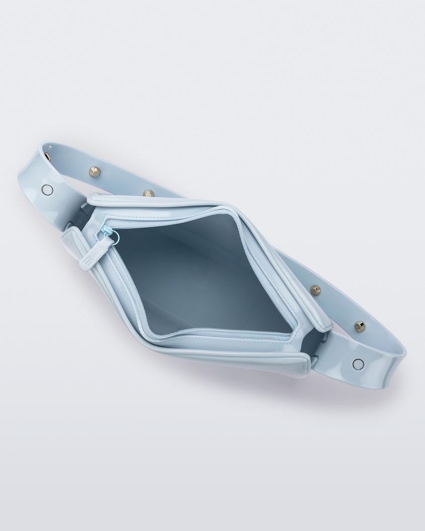 Top view of the blue Melissa Baguete Studs bag with a short studded strap, zipper undone to reveal the inside of the bag.