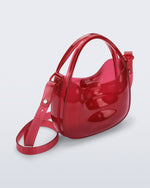 Angled view of a clear red Mirror bag with cross body straps two clear handles.