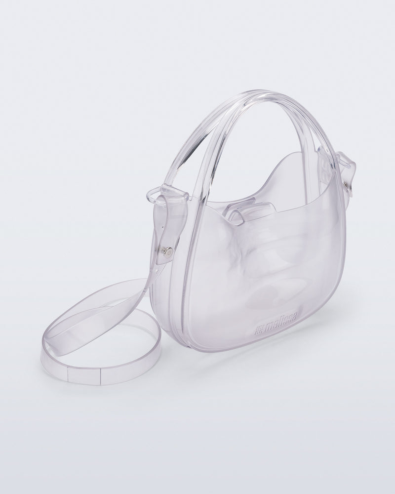 Angled view of a clear Mirror bag with cross body straps two clear handles.