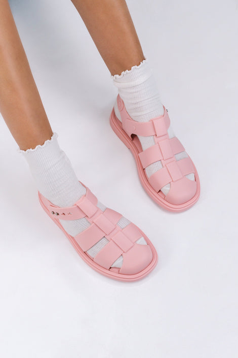 Model's legs in white socks wearing a pair of pink Emma women's sandals.