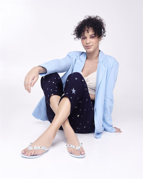 Model in star capris and blue blazer wearing a pair of blue Melissa Harmonic Studs flip flops with gold studs on the upper.