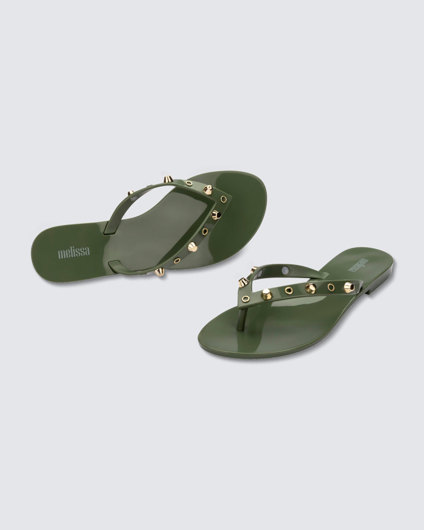 Angled and top view of a pair of green Melissa Harmonic Studs flip flops with gold studs on the upper.