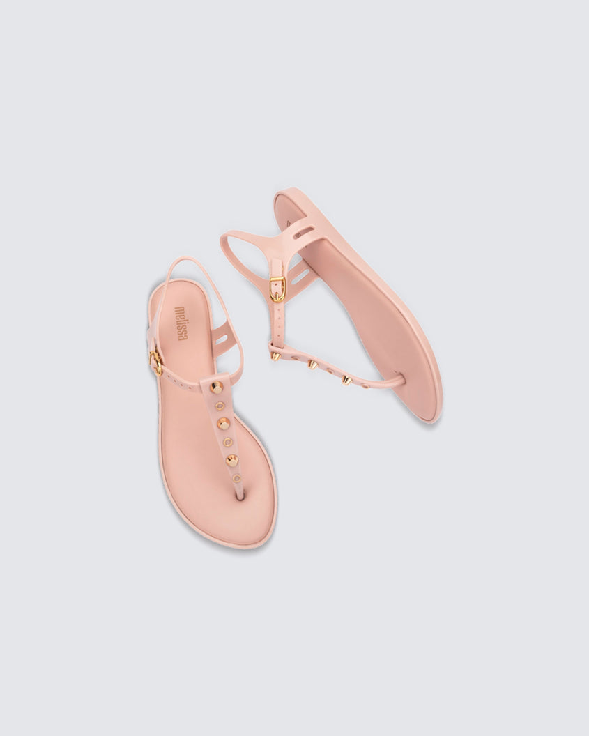 Top and side view of a pair of pink Melissa Solar studs sandals with gold studded t-strap and gold buckle.