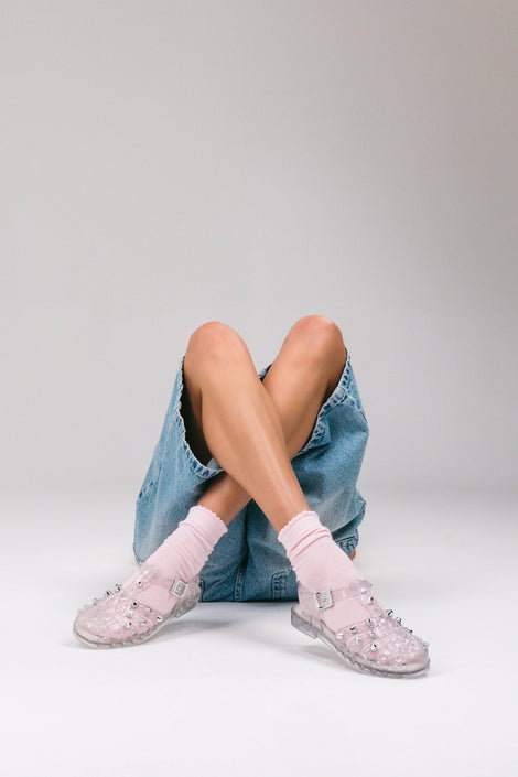 Model's legs in jean shorts and pink socks wearing a pair of clear Possession Stud fisherman sandals