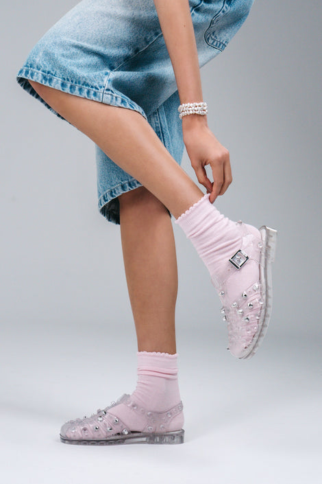 Model's legs in jean shorts and pink socks wearing a pair of clear Possession Stud fisherman sandals