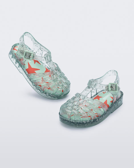 Angled view of a pair of clear star glitter green Possession baby fisherman sandals