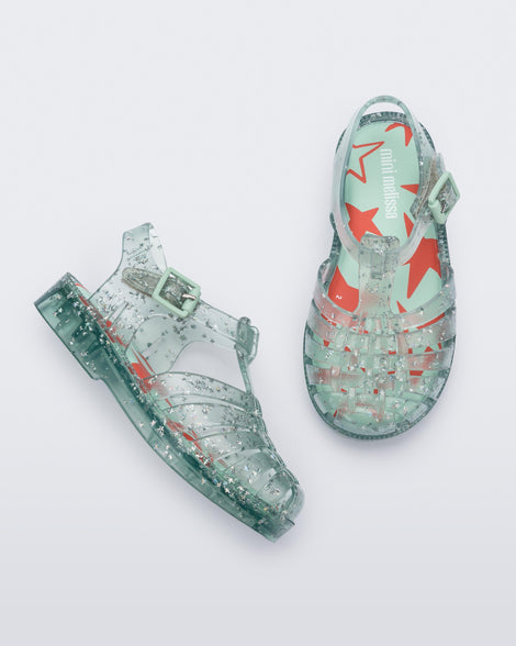 Side and top view of a pair of clear star glitter green Possession baby fisherman sandals