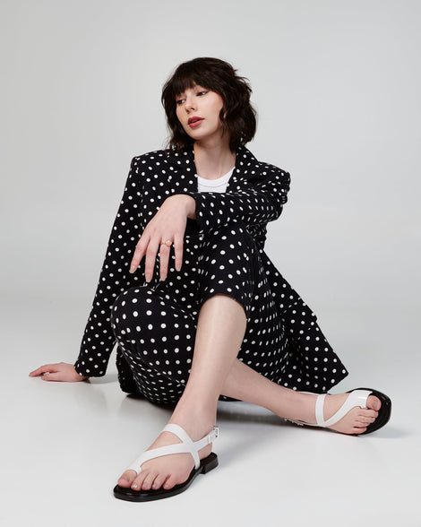 Model wearing a polka dot suit wearing a pair of white Cassie sandals.