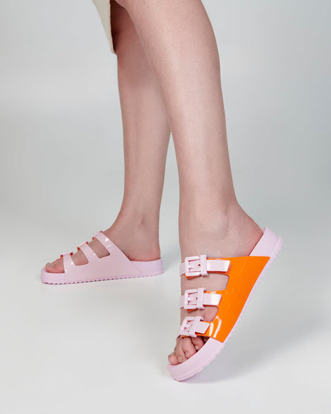 Model's legs wearing a pair of pink and orange Cozy Stripes slides