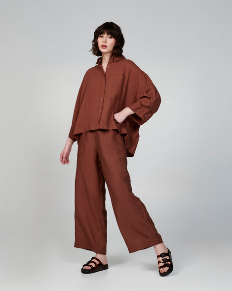 Model in a brown outfit wearing a pair of black Cozy Stripes slides with tortoise colored straps