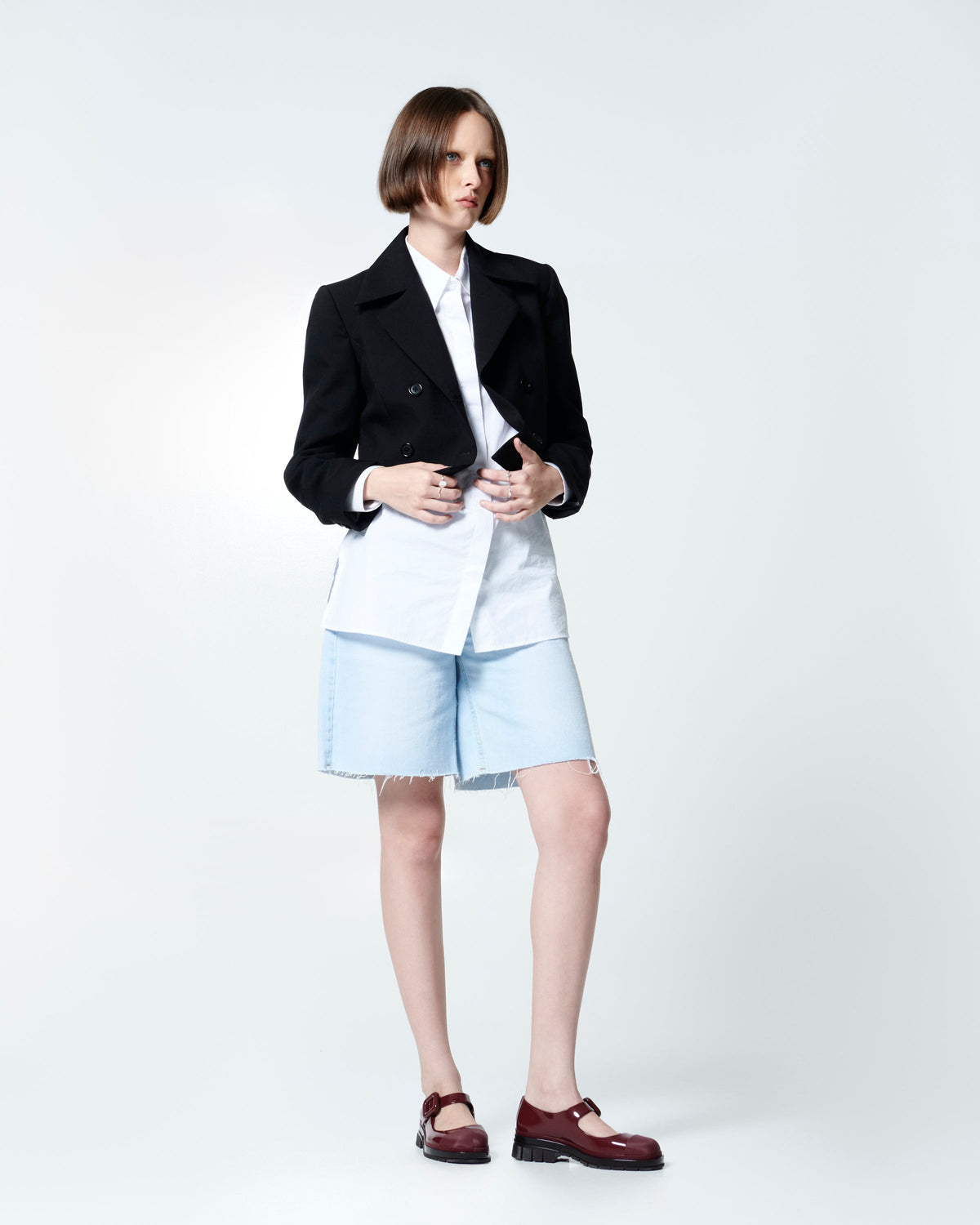Model in jean shorts and a blazer wearing a pair of burgundy June mary janes with matte
