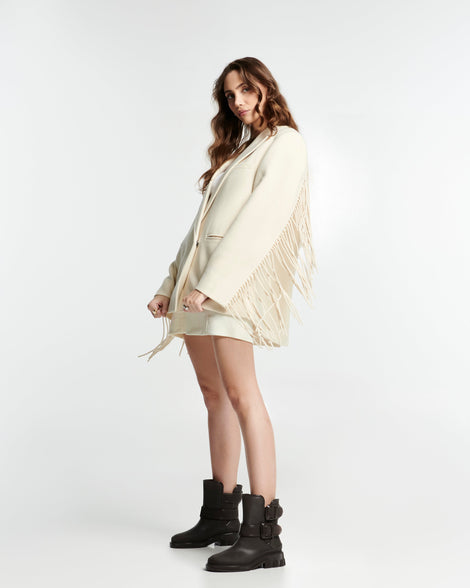 Model in a cream colored outfit wearing a pair of brown Bang boots with side buckles