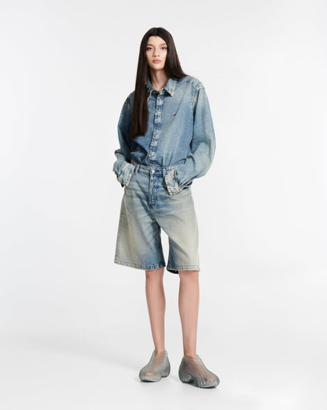 Model in jean shorts and a jean button down wearing a pair of a transparent green Quantum Sneakers + Diesel