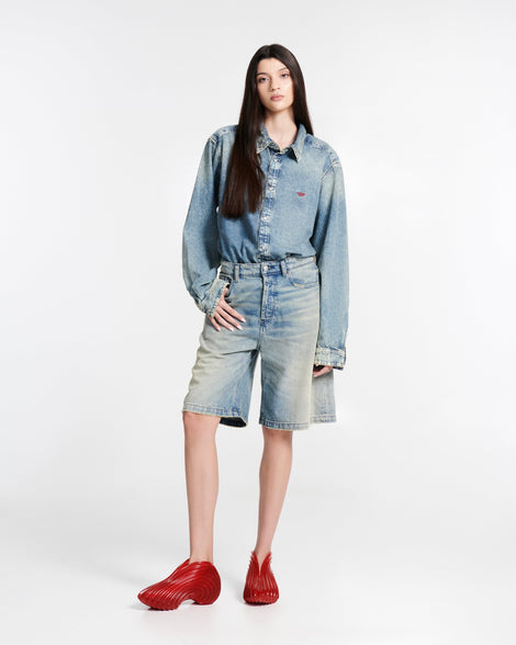 Model in jean shorts and a jean button down wearing a pair of transparent red Quantum Sneakers + Diesel