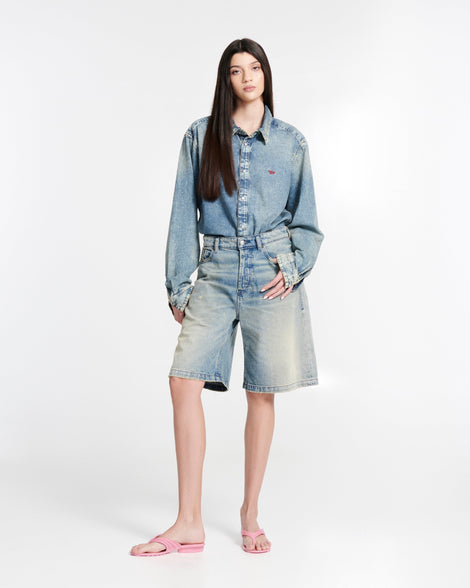 Model in jean shorts and jean button down shirt wearing a pair of pink Flip Flop + Diesel sandals