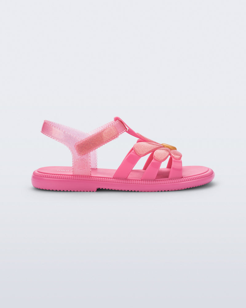 Side view of a glitter pink Hip Bloomy kids sandal with pink daisy on top