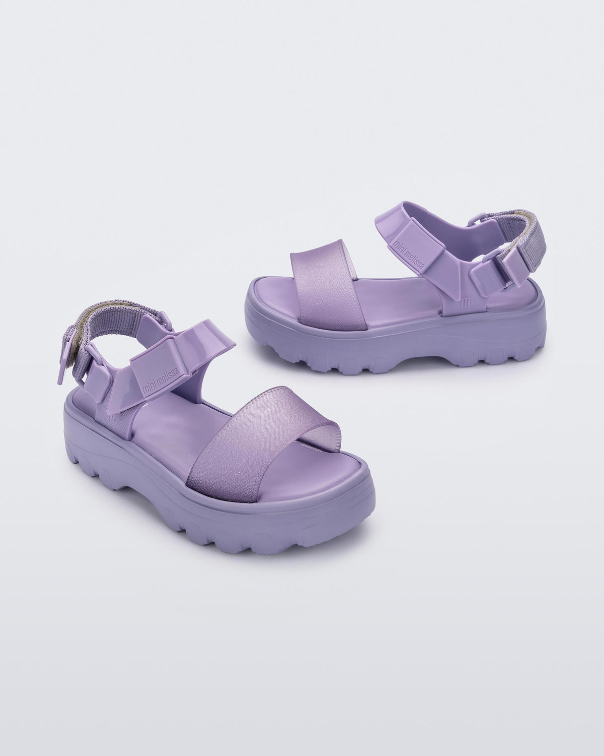 Angled view of a pair of Mini Melissa Kick Off platform sandals in lilac with adjustable velcro ankle straps