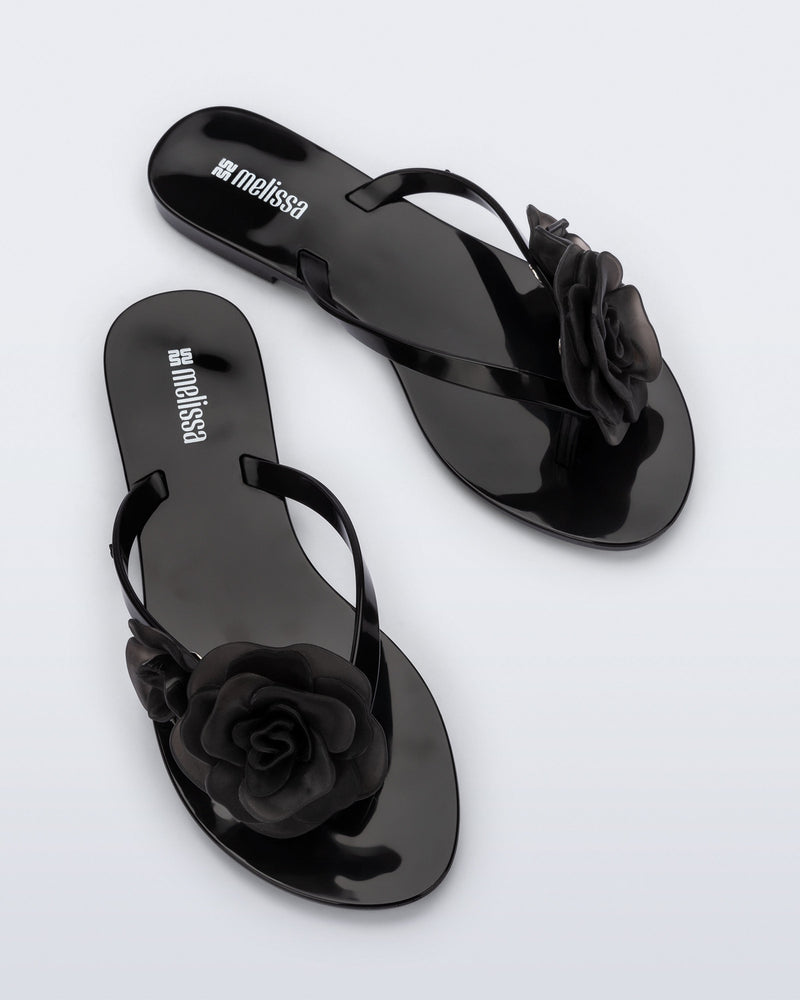 Top view of a pair of black Harmonic Petals flip Flop with black flowers on top