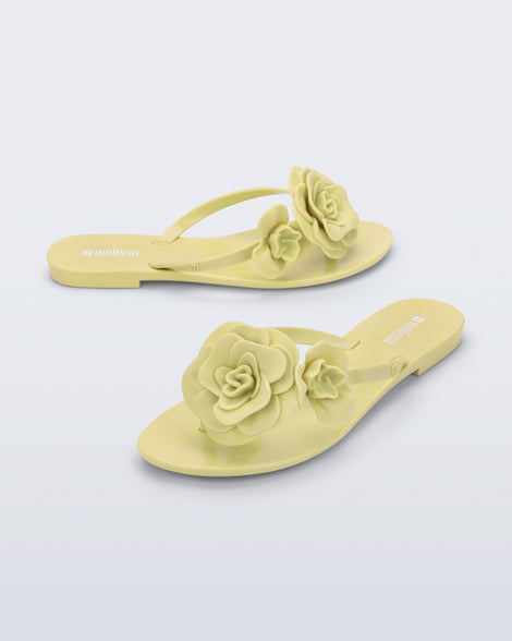 Side and angled view of a pair of green Harmonic Petals flip Flop with green flowers on top