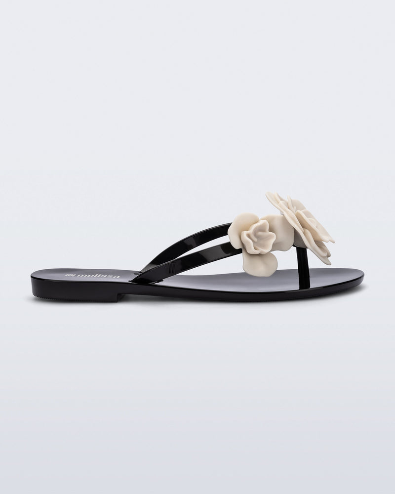Side view of a black Harmonic Petals flip Flop with beige flowers on top