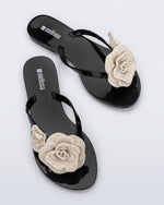 Top view of a pair of black Harmonic Petals flip Flop with beige flowers on top