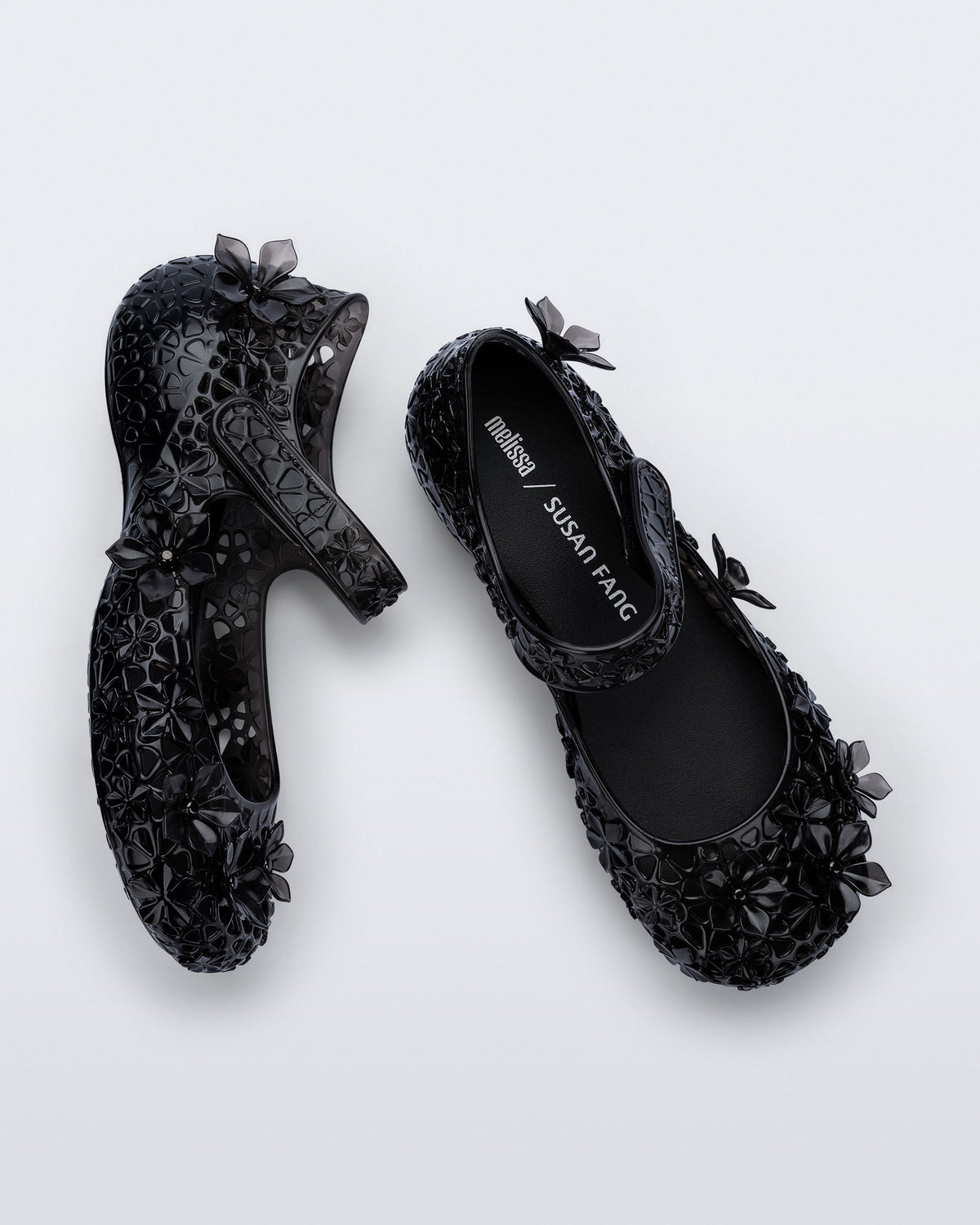 Top and side angled view of a pair of clear black Melissa + Susan Fang Luna Bloom flats with flower adornments