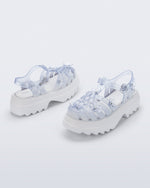 Back and side angled view of a pair of Clear Melissa + Susan Fang Possession Platform Sakura sandals with white soles
