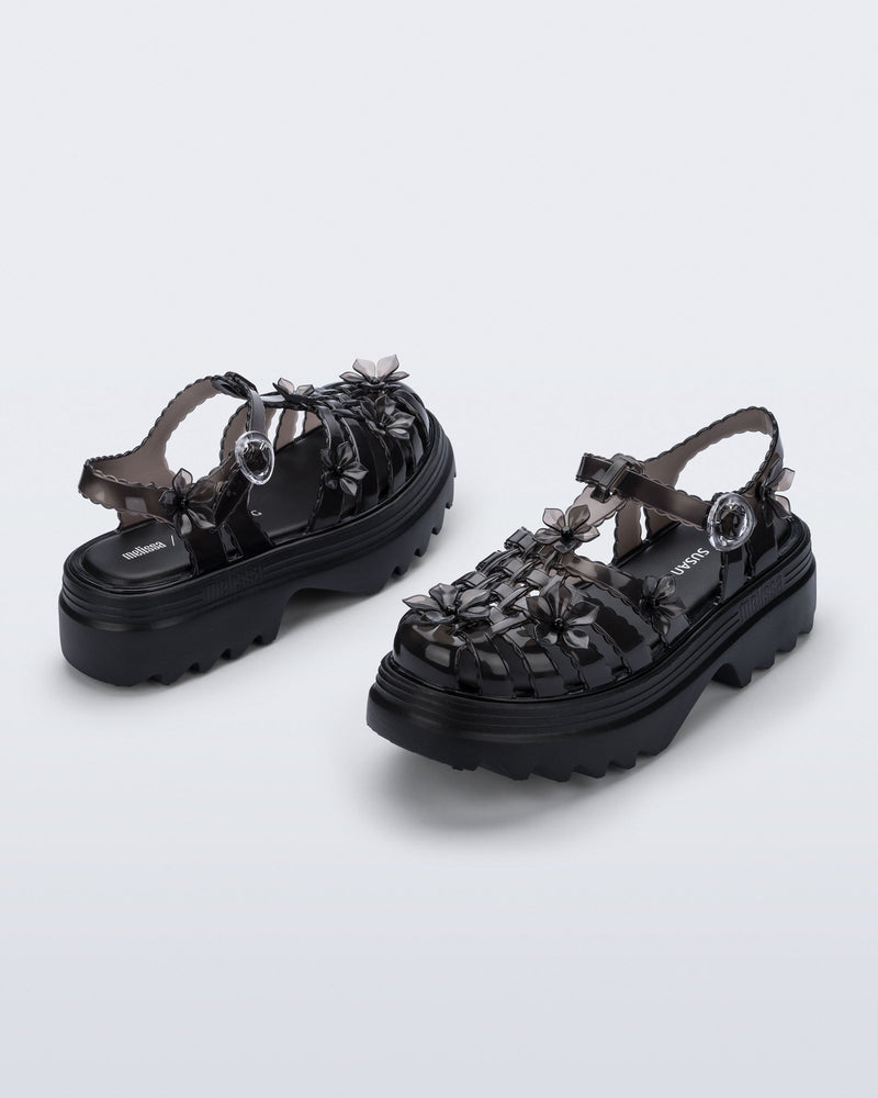 Back and side angled view of a pair of Clear black Melissa + Susan Fang Possession Platform Sakura sandals