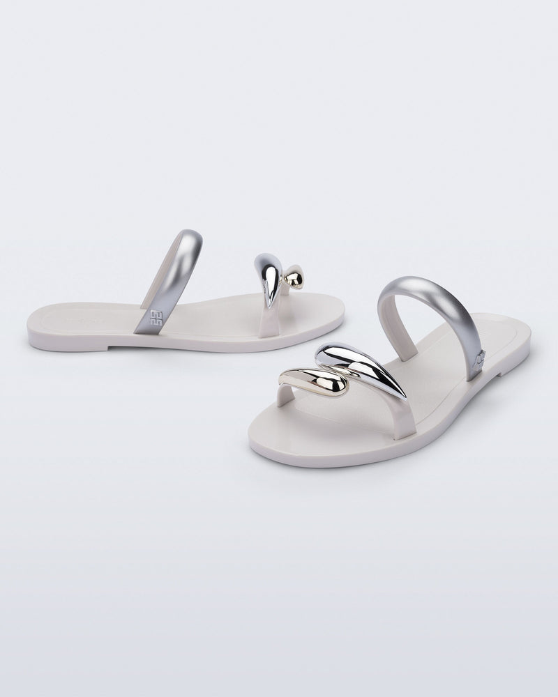 Side and angled view of a pair of white Eden sandals with metallic straps