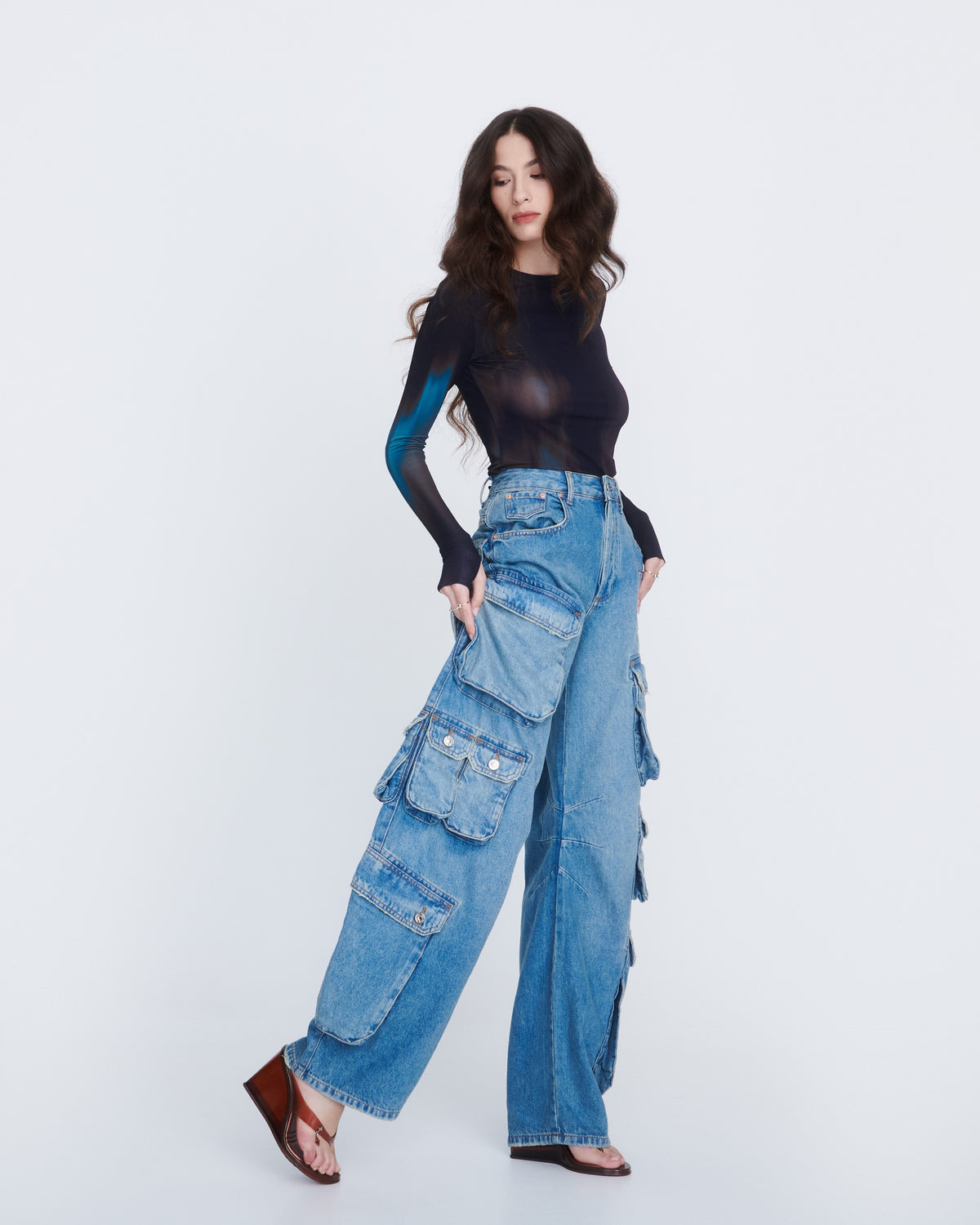 A model in a jeans and black shirt wearing a pair of clear brown Nabeela heel wedge shoes